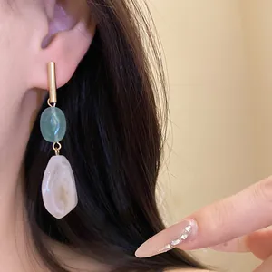 Detailed view of vintage geometric resin drop earrings worn on an ear with gold accents