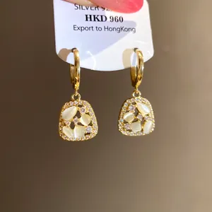 Detail of 14k gold plated drop earrings with zircon and cat's eye stones on a card