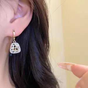 Close-up of elegant 14k gold plated dangling earrings with zircons and opals on ear