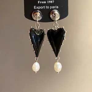 Elegant heart-shaped drop earrings featuring black resin and white pearl accents.