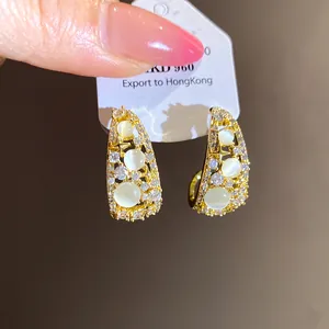 Detail of 14k gold plated C-shaped earrings featuring sparkling zircons and opal stones