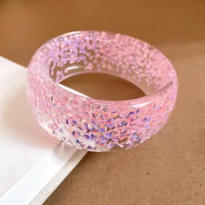 Primo piano di un bracciale in resina rosa con frammenti di glitter olografici iridescenti