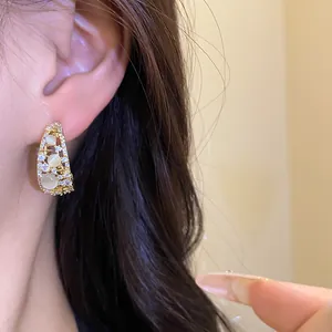 Detailed close-up of 14k gold-plated C-shaped earring with sparkling zircons