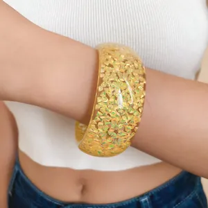 Primo piano di un bracciale in resina con glitter dorati olografici triangolari.