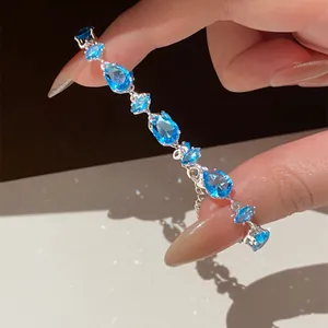 Close-up of elegant silver bracelet with blue marquise and pear-cut zircon crystals.