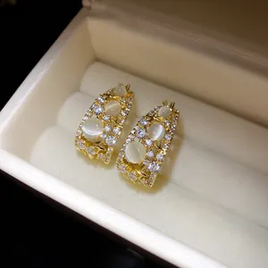 Close-up of 14k gold plated C-shape earrings with zircon and cat-eye stones in a jewelry box