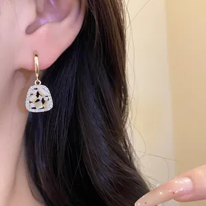 Elegant 14k gold-plated trapezoid earrings with zirconia and cat-eye stones worn by model