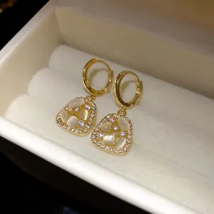Macro view of gold hoop earrings with cat-eye stone and zircon pavé detail