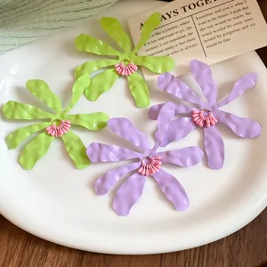 Detailed macro view of colorful matte pleated flower earrings in green and purple hues