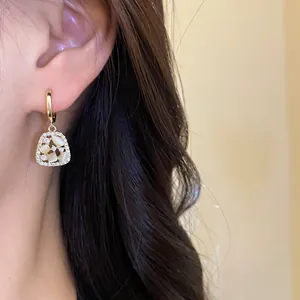 Close-up of 14k gold plated drop earring with zircon and opal-like stones