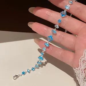 Detailed macro view of a silver bracelet featuring vibrant blue geometric zircon stones.