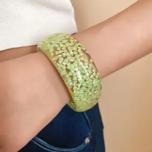 Primo piano dettagliato dei fiocchi verdi cangianti all'interno di un bracciale in resina.