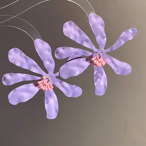 Macro detail of elegant purple ruffled flower pendant earrings with pink stamen accents