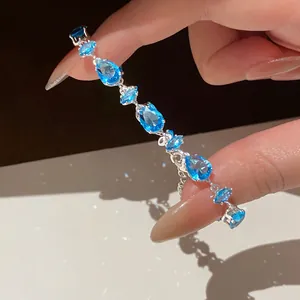 Close-up detail of a silver bracelet featuring vivid blue pear and oval zircons