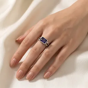 Close-up of a vintage Cuban link chain ring with a rectangular purple zircon on a finger
