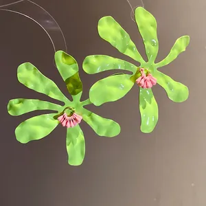 Macro view of neon green wrinkled flower earrings with pink floral stamen details
