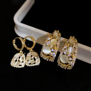 Macro view of 14k gold plated C-shaped earrings with cat's eye stones and zircons