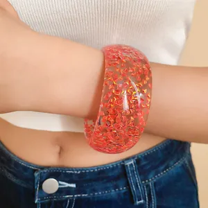 Vista dettagliata di un grosso bracciale in resina trasparente con glitter arancioni cangianti