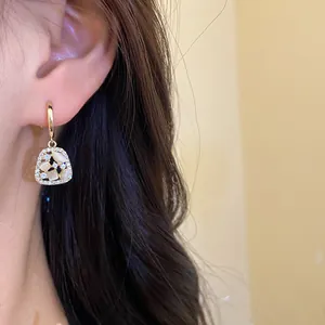 Close-up detail of 14k gold plated C-shaped earrings with cat eye stone and zircons