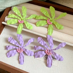 Close-up of vibrant green and purple enamel flower earrings displayed in a jewelry tray