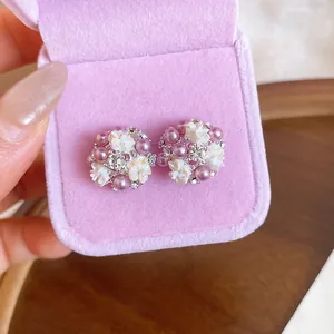 Close-up of French floral earrings with purple pearls and rhinestones in a pink box