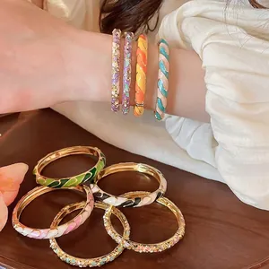 Bracelets en émail floral de style chinois doré, portés au poignet et posés sur bois