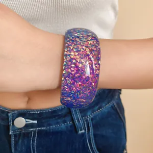 Dettaglio di un elegante bracciale in resina blu iridescente con glitter colorati posto al polso