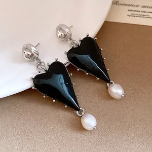 Close-up of black heart drop earrings with white pearl pendants and silver needles