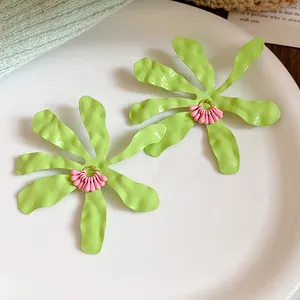 Detail view of lime green flower earrings with wavy petals and pink center beads.
