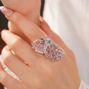 Detailed view of an elegant butterfly wing ring with pink zircon stones on a finger