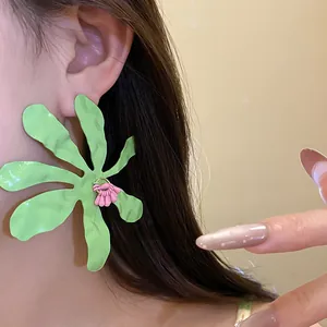 Close-up of vibrant green wrinkled flower earrings with pink center detail on model's ear