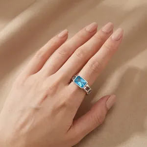 Close-up of a silver Cuban link ring with a vibrant rectangular blue zircon gemstone