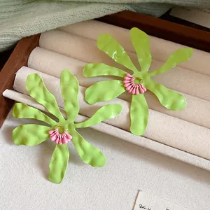 Close-up view of lime green enamel flower earrings with pink details.