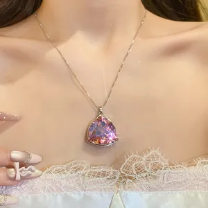 Dettaglio di una collana con ciondolo a triangolo geometrico in cristallo rosa sul collo
