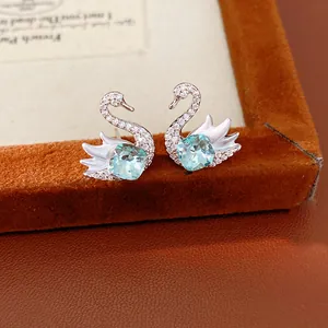 Close-up of silver swan stud earrings with blue crystals and zircon pavé detailing