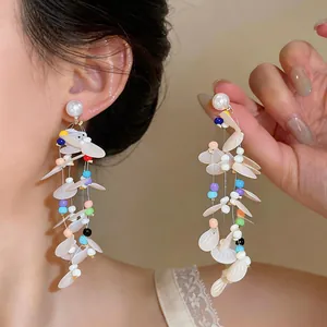 Macro view of elegant fairy style pearl tassel earrings with colorful beads and sequins