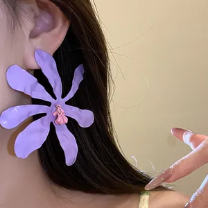 Macro view of purple enamel flower drop earring on ear, showing delicate petal texture.
