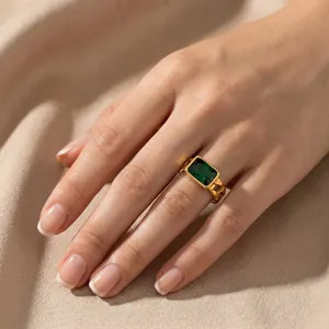 Close-up view of a vintage gold-plated Cuban chain ring with a green emerald-cut zircon