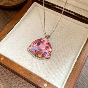 Dettaglio di una collana con ciondolo triangolare in cristallo rosa in scatola legno