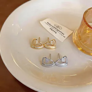 Detailed view of gold and silver twisted heart earrings with sparkling zircons
