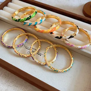 Vue détaillée de divers joncs en émail coloré et or dans une boîte à bijoux.