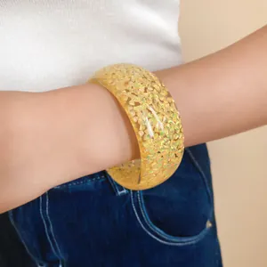 Primo piano di un elegante bracciale rigido in resina con scaglie di glitter olografici gialli