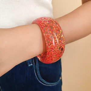 Vista dettagliata di un bracciale rigido in resina cangiante con glitter rossi vivaci.