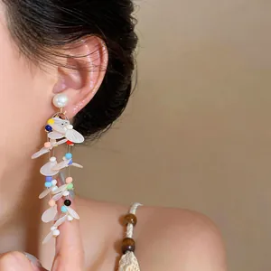 Detailed shot of fairy style pearl earrings with colorful beads and white sequin tassels