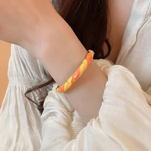 Détail d'un bracelet jonc en émail coloré porté au poignet d'un modèle au style élégant