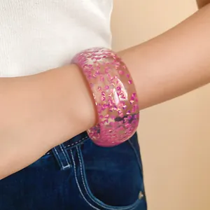 Dettaglio di un bracciale in resina trasparente con glitter rosa cangianti al polso