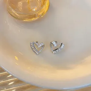 Detailed view of silver heart stud earrings with twisted design and zircon inlay