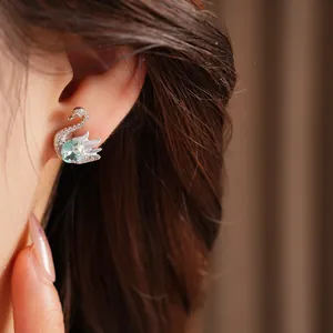 Close-up detail shot of a silver swan stud earring with sparkling aquamarine and crystals
