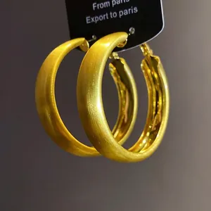 Elegant brushed gold hoop earrings with minimalist circular design and matte finish