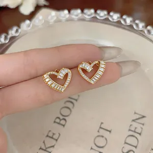 Close-up of elegant gold-plated heart stud earrings with sparkling baguette zircons